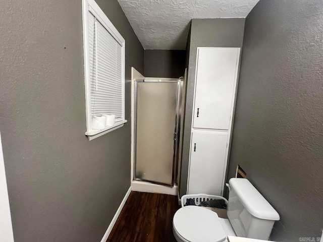 bathroom featuring wood-type flooring, a textured ceiling, toilet, and an enclosed shower