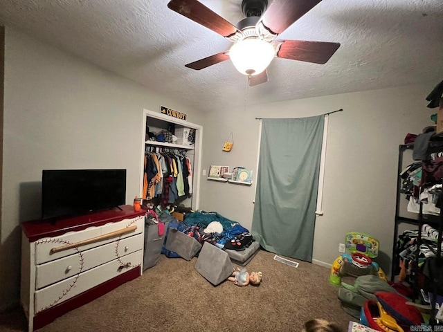 carpeted bedroom featuring ceiling fan, a closet, and a textured ceiling