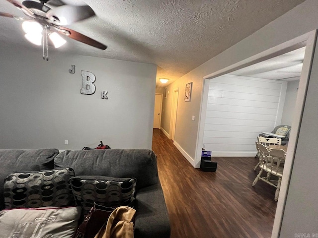 living room with ceiling fan, dark wood-type flooring, and a textured ceiling