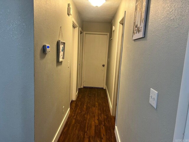 hallway with dark wood-type flooring and a textured ceiling