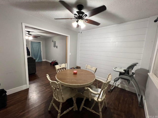 dining area featuring wooden walls, dark hardwood / wood-style flooring, and a textured ceiling