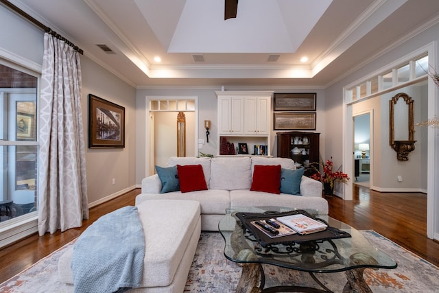 living room with a raised ceiling, ornamental molding, and dark hardwood / wood-style flooring