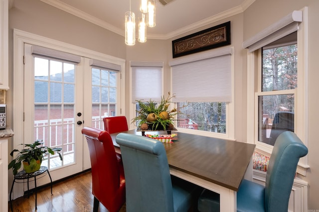 dining area with french doors, a water view, a healthy amount of sunlight, and hardwood / wood-style floors