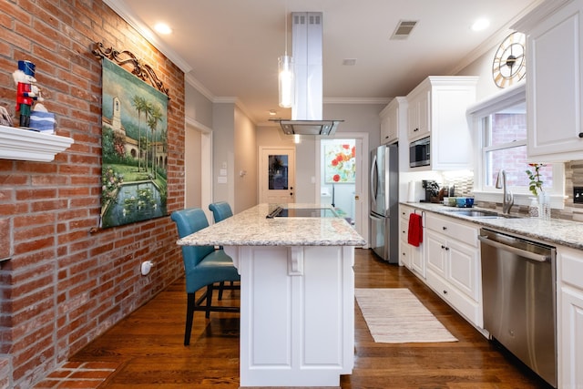 kitchen featuring appliances with stainless steel finishes, white cabinetry, light stone counters, a kitchen bar, and a center island