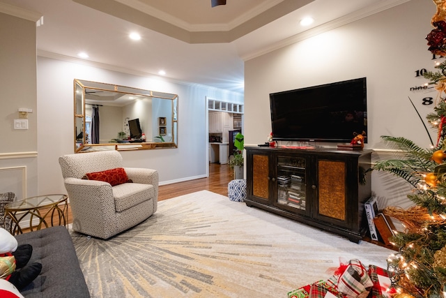 living room featuring hardwood / wood-style flooring, a raised ceiling, and ornamental molding