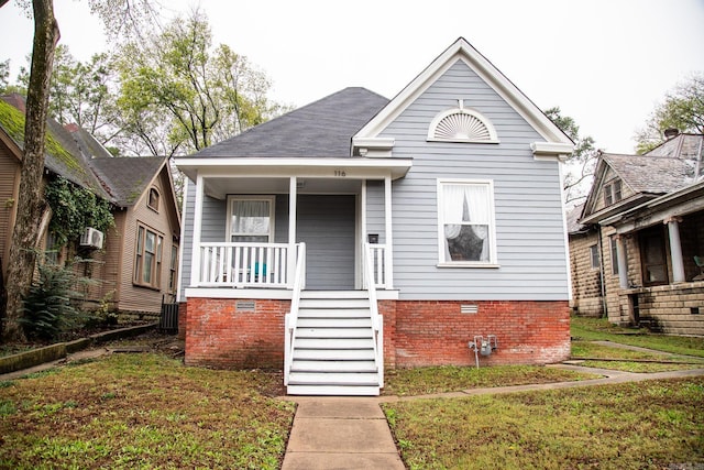 bungalow-style home with covered porch and a front yard