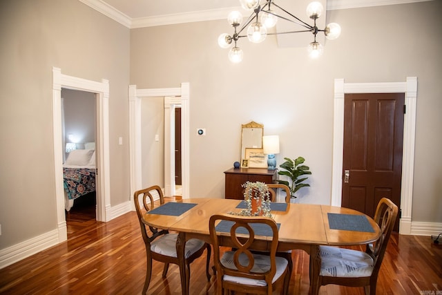 dining area featuring dark wood-type flooring, ornamental molding, and an inviting chandelier