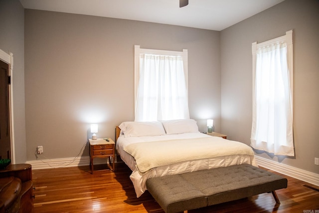 bedroom with multiple windows, ceiling fan, and hardwood / wood-style flooring