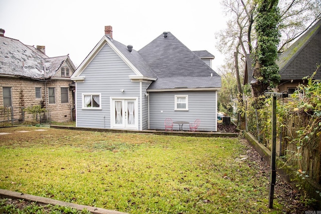 back of house with french doors and a lawn