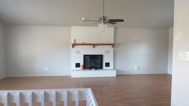 unfurnished living room featuring a fireplace, a textured ceiling, and ceiling fan