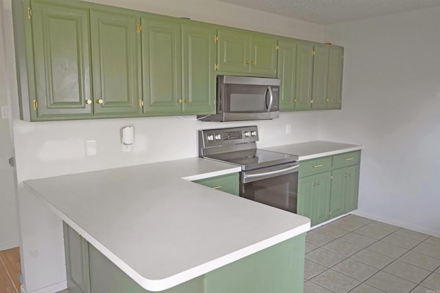 kitchen featuring green cabinets, light tile patterned floors, a textured ceiling, kitchen peninsula, and stainless steel appliances