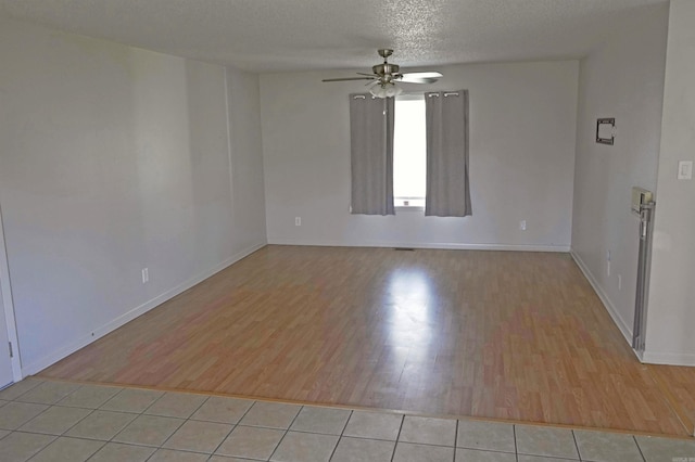 unfurnished room with ceiling fan, light tile patterned floors, and a textured ceiling