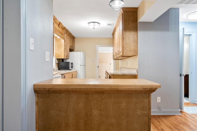 kitchen featuring kitchen peninsula, white refrigerator, and light hardwood / wood-style flooring