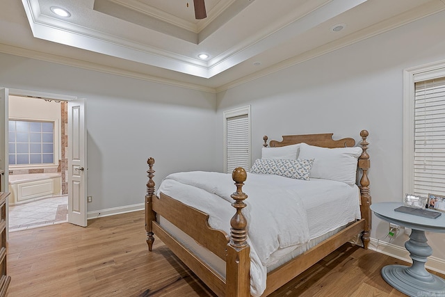 bedroom featuring connected bathroom, ceiling fan, a raised ceiling, crown molding, and hardwood / wood-style floors