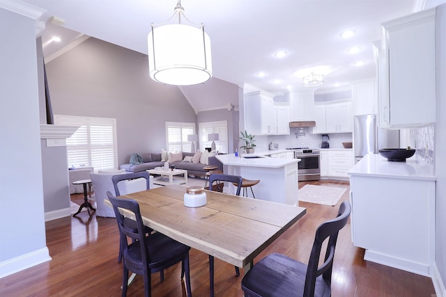 dining room with sink, dark hardwood / wood-style floors, lofted ceiling, and ornamental molding