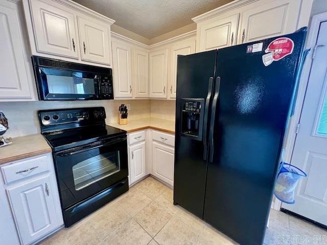 kitchen featuring black appliances, light tile patterned flooring, and white cabinets