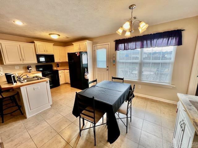 kitchen featuring white cabinets, a notable chandelier, decorative light fixtures, light tile patterned flooring, and black appliances