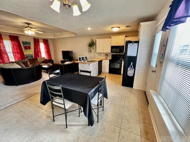 tiled dining room featuring a raised ceiling and ceiling fan