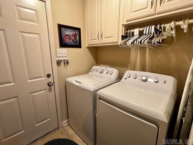 laundry area with cabinets, light tile patterned floors, and washing machine and dryer