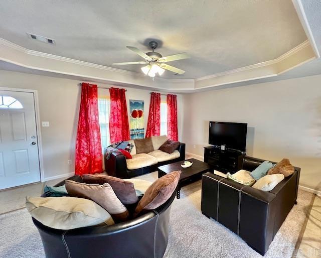 carpeted living room featuring a raised ceiling, ceiling fan, and crown molding