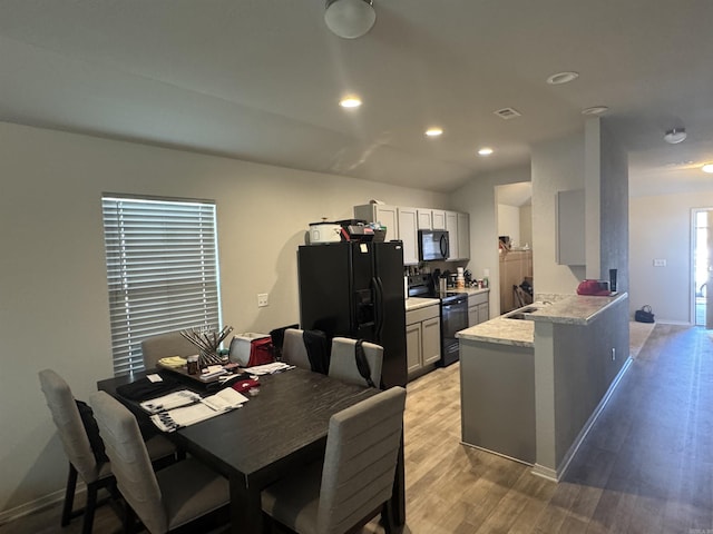 dining area featuring lofted ceiling, sink, and light wood-type flooring