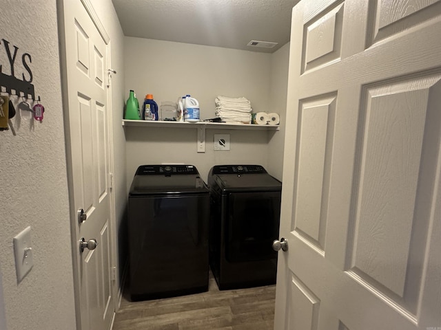 laundry room featuring separate washer and dryer, hardwood / wood-style flooring, and a textured ceiling