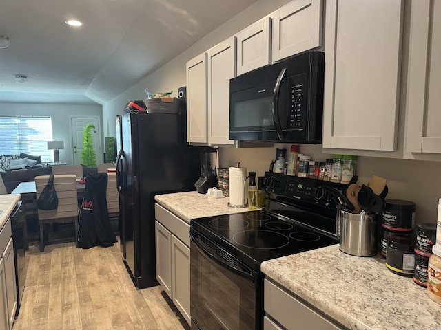 kitchen with white cabinetry, lofted ceiling, light wood-type flooring, and black appliances