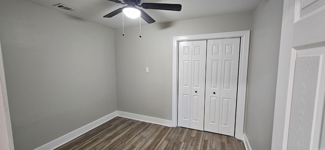 unfurnished bedroom with dark hardwood / wood-style flooring, a closet, and ceiling fan