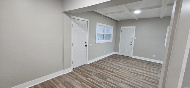 empty room featuring beam ceiling, coffered ceiling, and hardwood / wood-style flooring