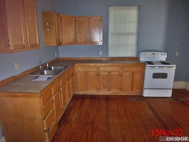 kitchen with white electric range, tile countertops, dark wood-type flooring, and sink