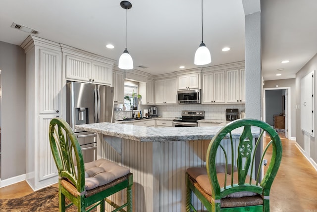 kitchen featuring a kitchen bar, kitchen peninsula, stainless steel appliances, and hanging light fixtures