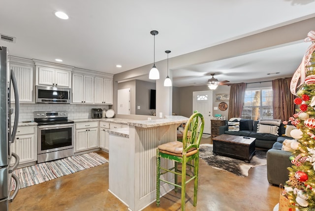 kitchen featuring a kitchen breakfast bar, kitchen peninsula, tasteful backsplash, white cabinetry, and stainless steel appliances