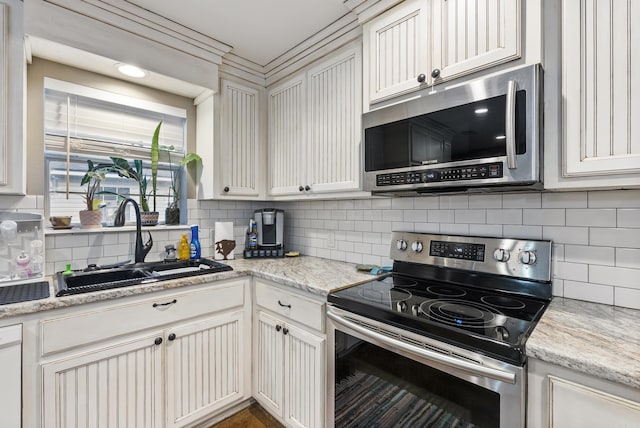 kitchen featuring tasteful backsplash, light stone countertops, sink, and stainless steel appliances