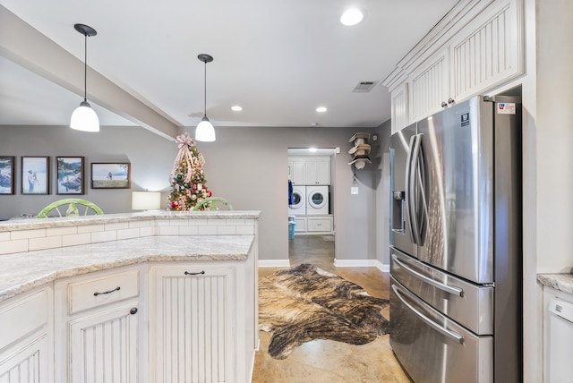 kitchen featuring white cabinetry, light stone counters, stainless steel fridge, white dishwasher, and washer and clothes dryer