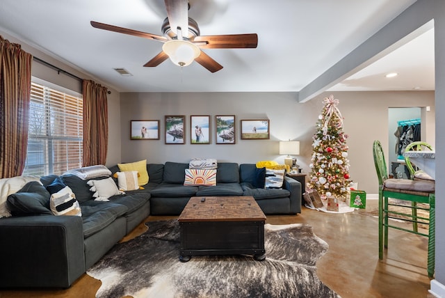 living room with beamed ceiling, ceiling fan, and concrete flooring