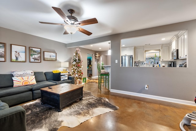 living room with concrete floors, ceiling fan, and sink