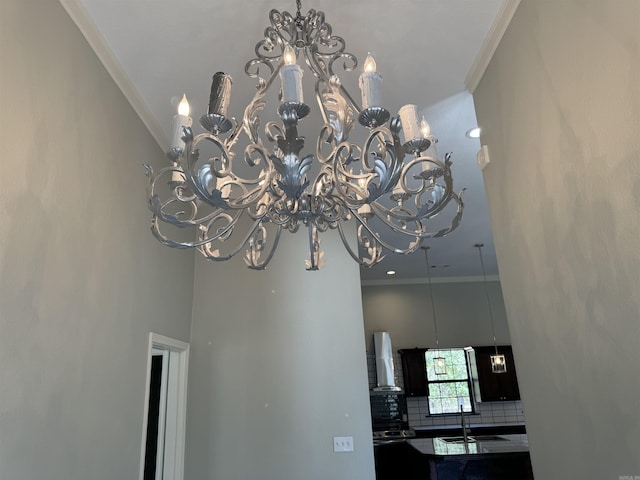 details featuring backsplash, wall chimney exhaust hood, ornamental molding, and a notable chandelier
