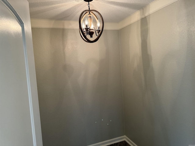 room details with a textured ceiling, ornamental molding, and a notable chandelier