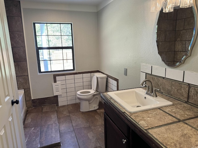 bathroom with toilet, vanity, tile walls, and ornamental molding