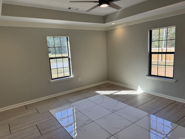 unfurnished room featuring a raised ceiling and ceiling fan