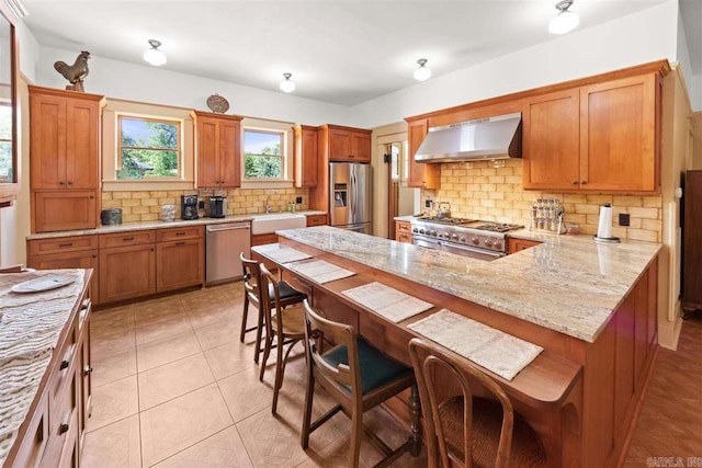 kitchen with a kitchen breakfast bar, wall chimney exhaust hood, tasteful backsplash, kitchen peninsula, and stainless steel appliances