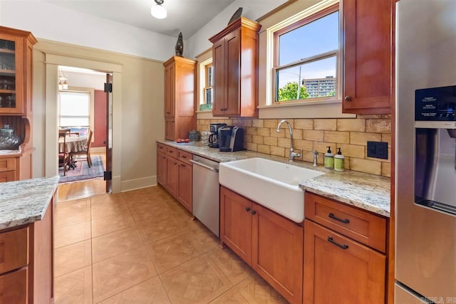 kitchen with backsplash, light stone countertops, sink, and stainless steel appliances