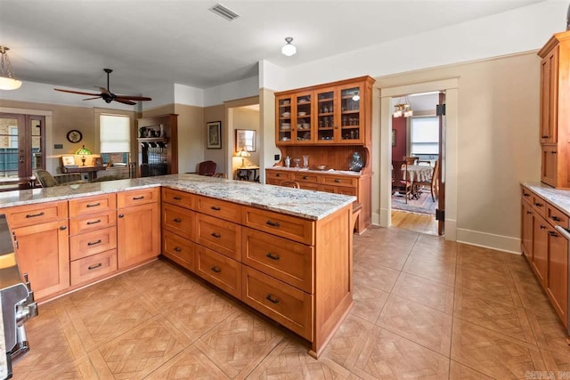 kitchen with pendant lighting, ceiling fan, light stone counters, and kitchen peninsula