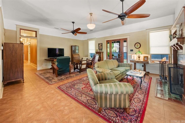 living room with a tile fireplace and ceiling fan