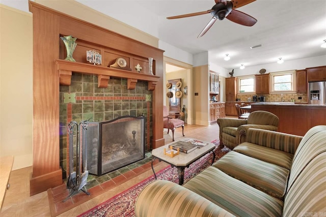 living room with a tiled fireplace and ceiling fan