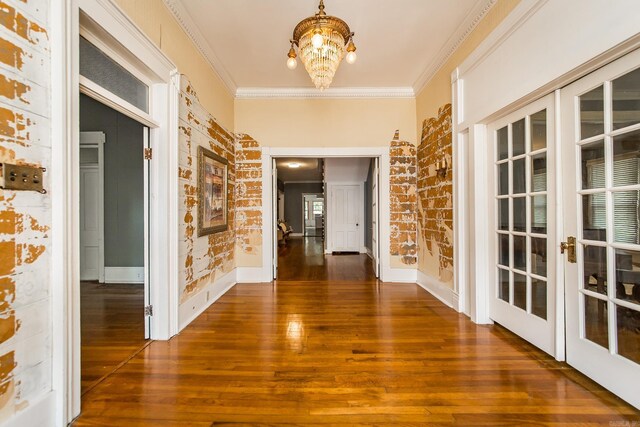 hall featuring dark hardwood / wood-style flooring, french doors, ornamental molding, and a chandelier