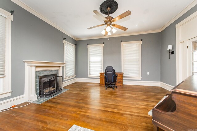 unfurnished living room with a tile fireplace, wood-type flooring, ceiling fan, and crown molding