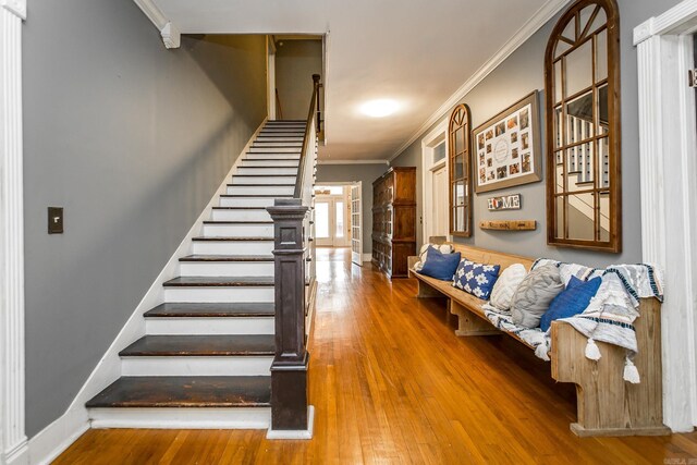 stairs featuring wood-type flooring and ornamental molding