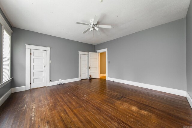 empty room with ceiling fan and dark wood-type flooring