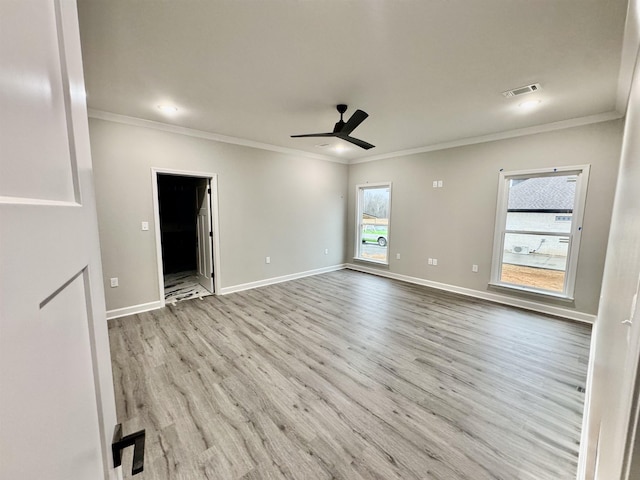 empty room featuring ceiling fan, visible vents, baseboards, light wood-style floors, and crown molding